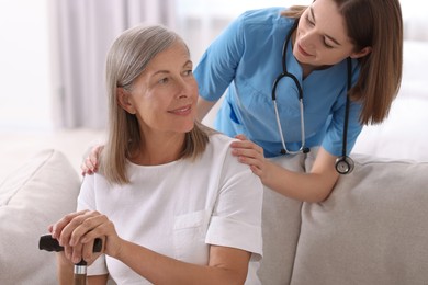 Young healthcare worker supporting senior patient indoors