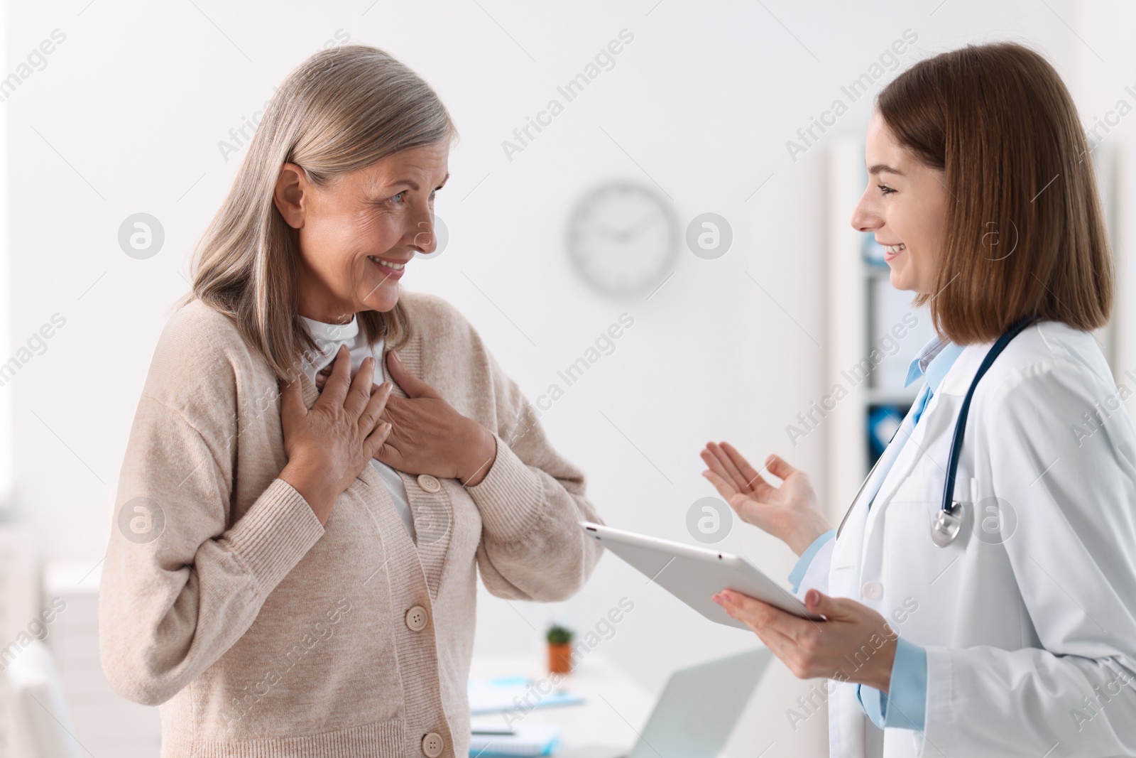 Photo of Smiling healthcare worker with tablet consulting senior patient in hospital