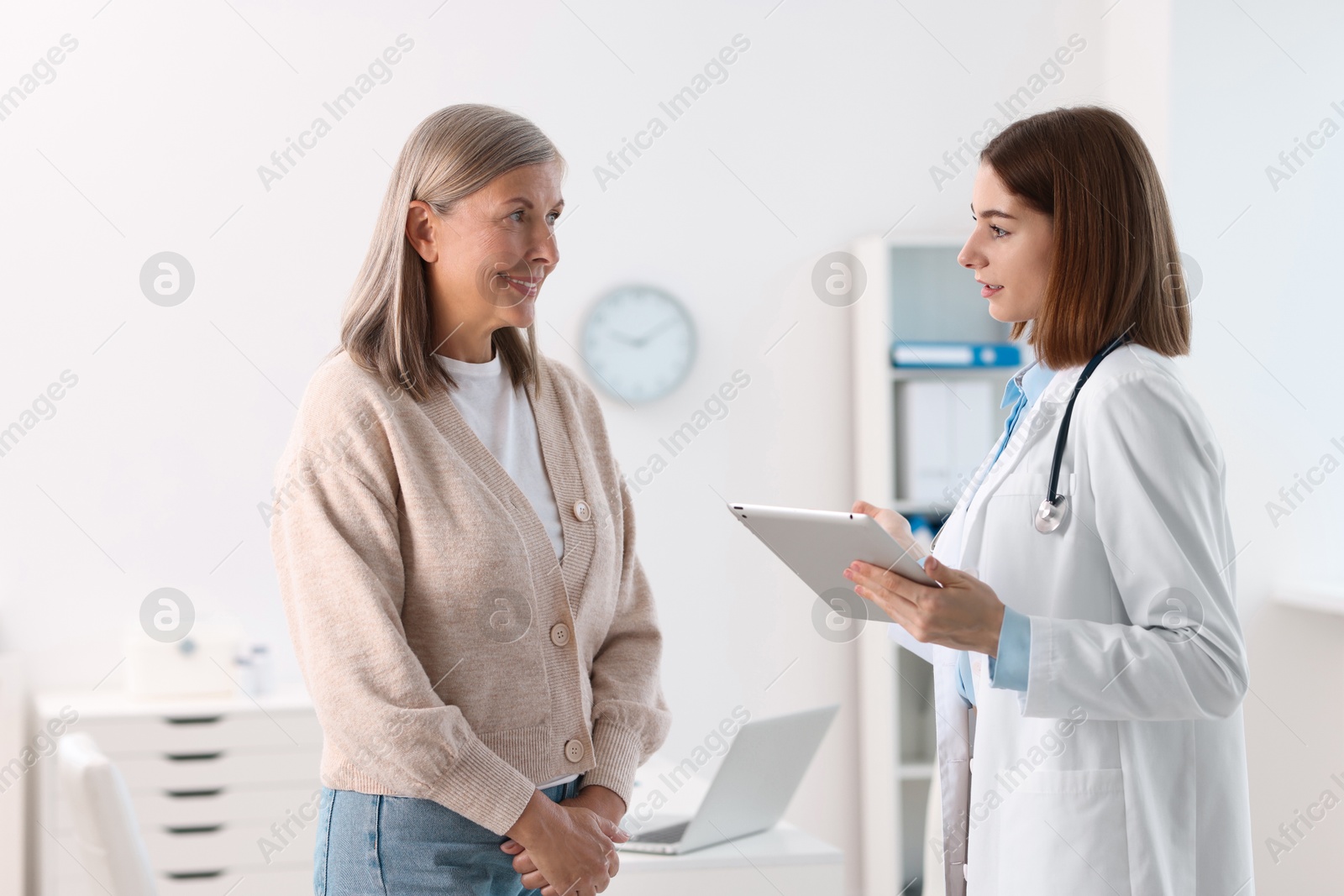 Photo of Young healthcare worker with tablet consulting senior patient in hospital