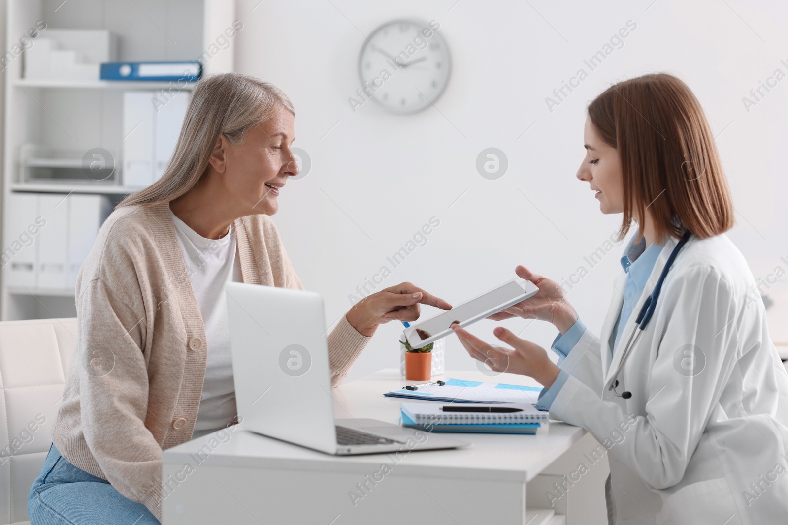 Photo of Healthcare worker and senior patient checking analysis results on tablet in hospital