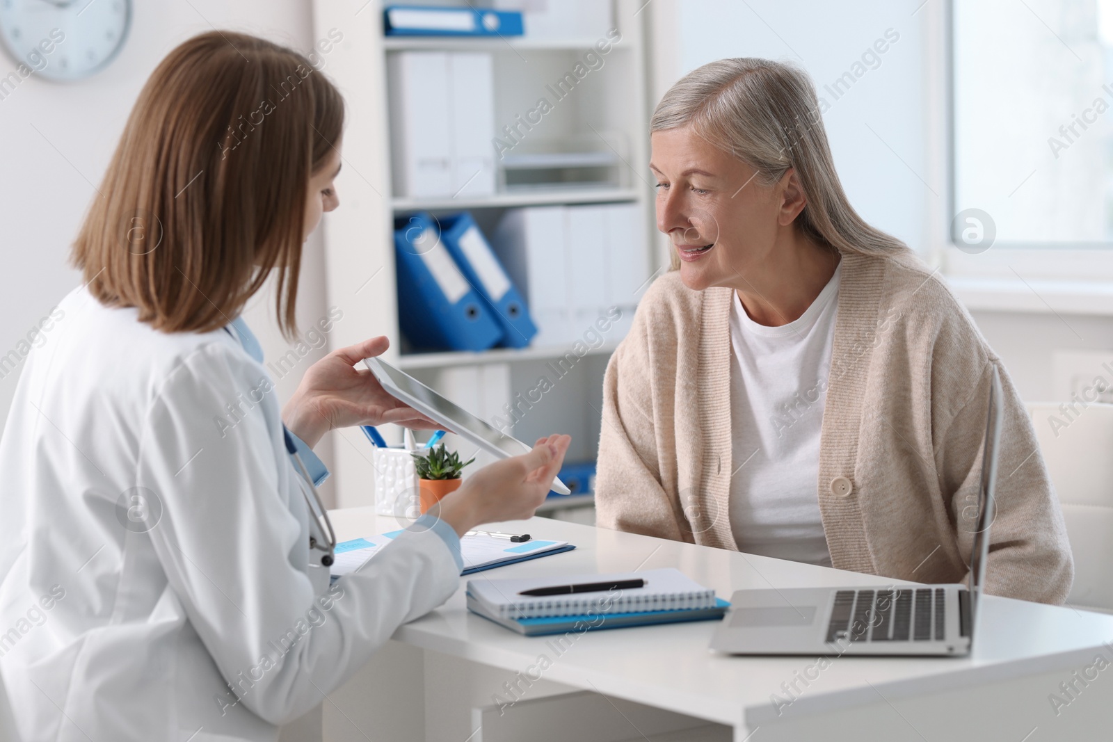 Photo of Healthcare worker and senior patient checking analysis results on tablet in hospital