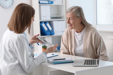 Healthcare worker and senior patient checking analysis results on tablet in hospital