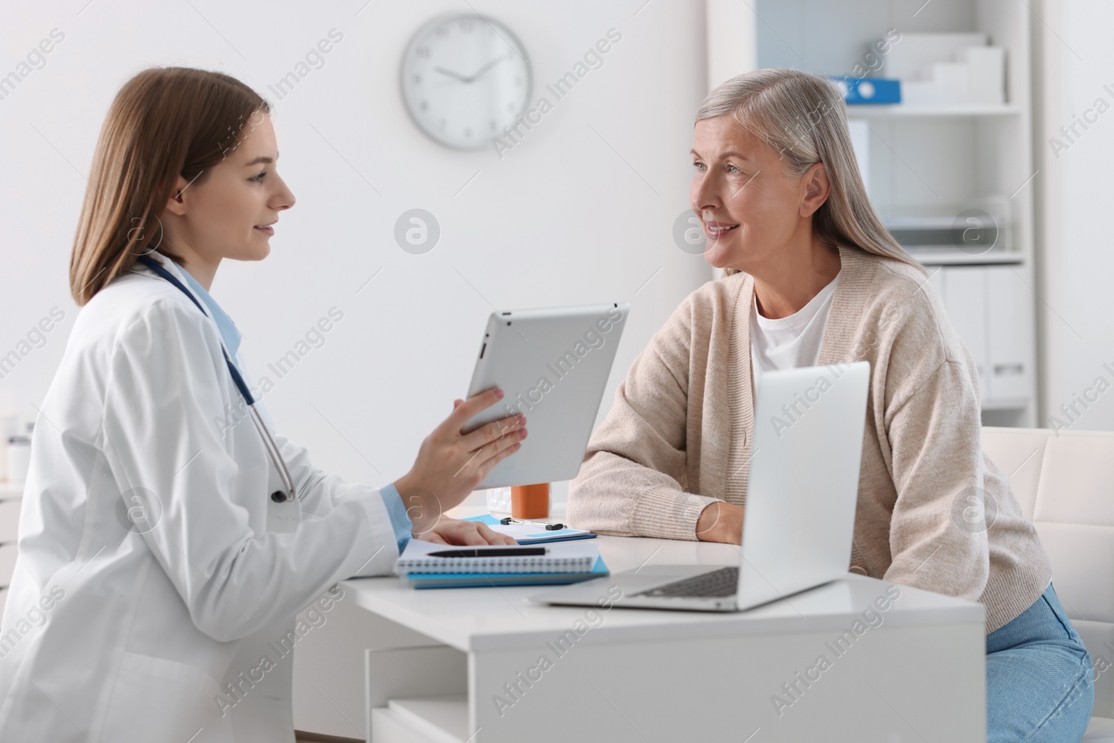 Photo of Smiling healthcare worker with tablet consulting senior patient in hospital