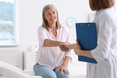 Photo of Smiling patient shaking hands with healthcare worker in hospital, closeup