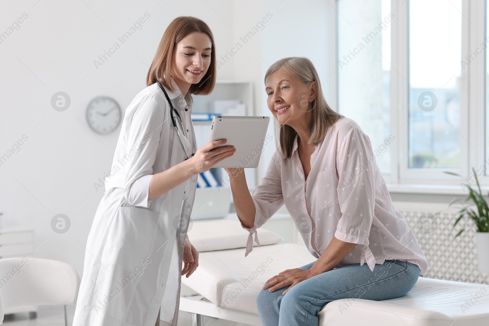 Photo of Smiling healthcare worker and senior patient checking analysis results on tablet in hospital