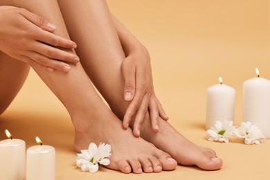 Photo of Woman touching her smooth feet on beige background, closeup