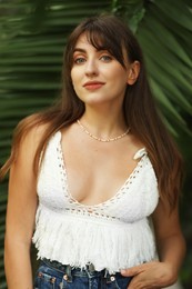 Photo of Portrait of beautiful woman near palm leaves outdoors