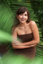 Portrait of smiling woman near palm leaves outdoors