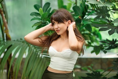 Beautiful woman posing near palm tree leaves