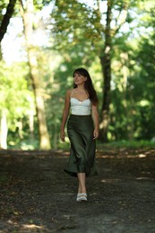 Full length portrait of beautiful woman walking in park