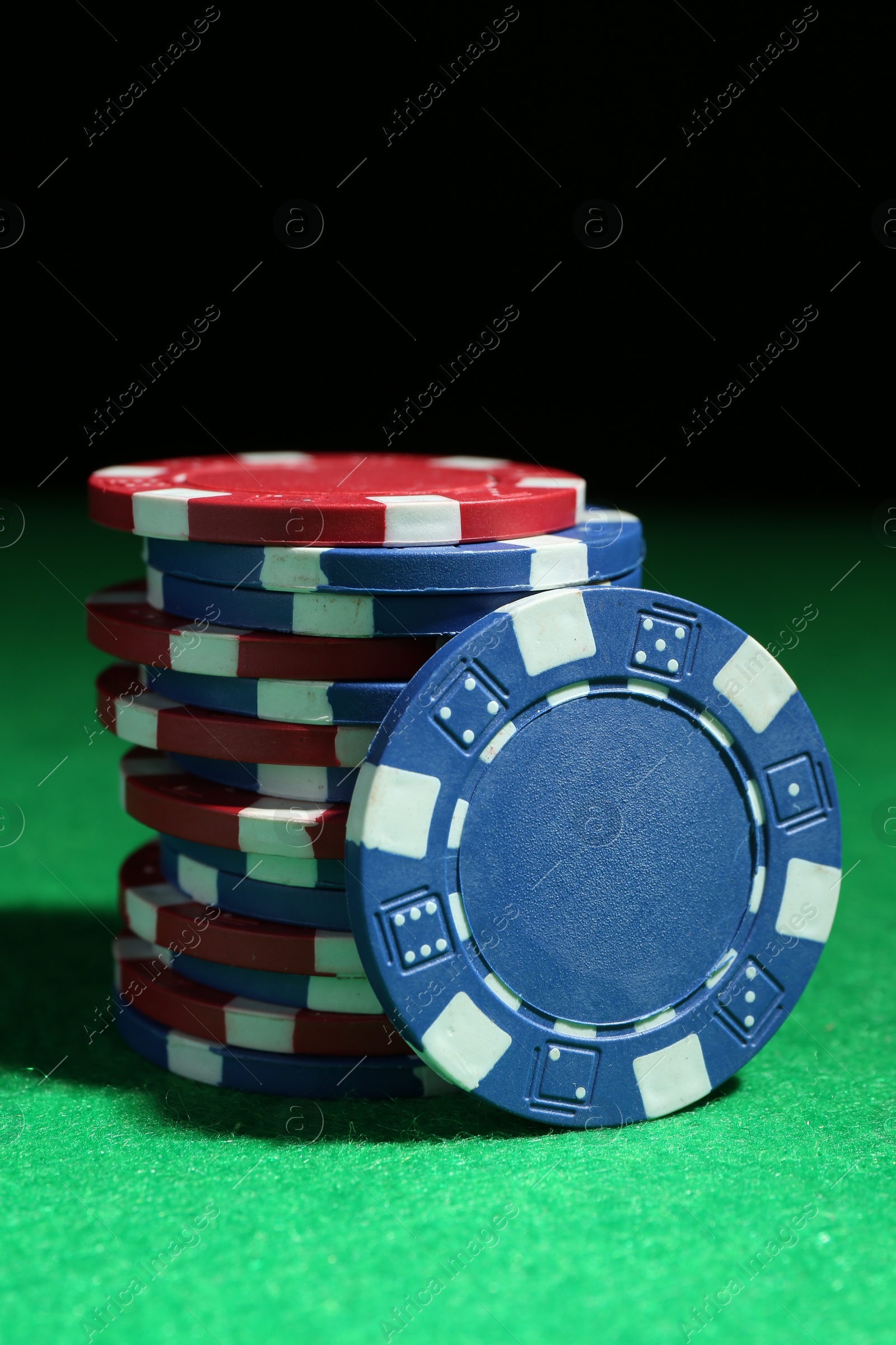 Photo of Poker chips on green table against dark background, closeup