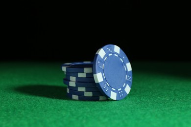 Photo of Poker chips on green table against dark background, closeup