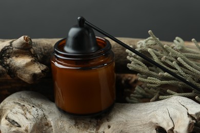 Candle, snuffer and brunia plants on pieces of decorative wood against gray background