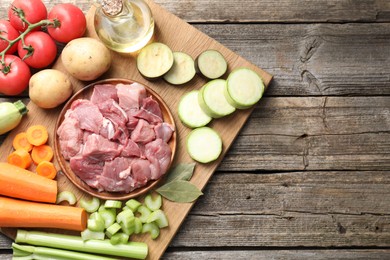 Photo of Cooking stew. Uncooked meat and vegetables on wooden table, top view. Space for text