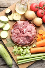 Photo of Cooking stew. Uncooked meat and vegetables on wooden table, top view