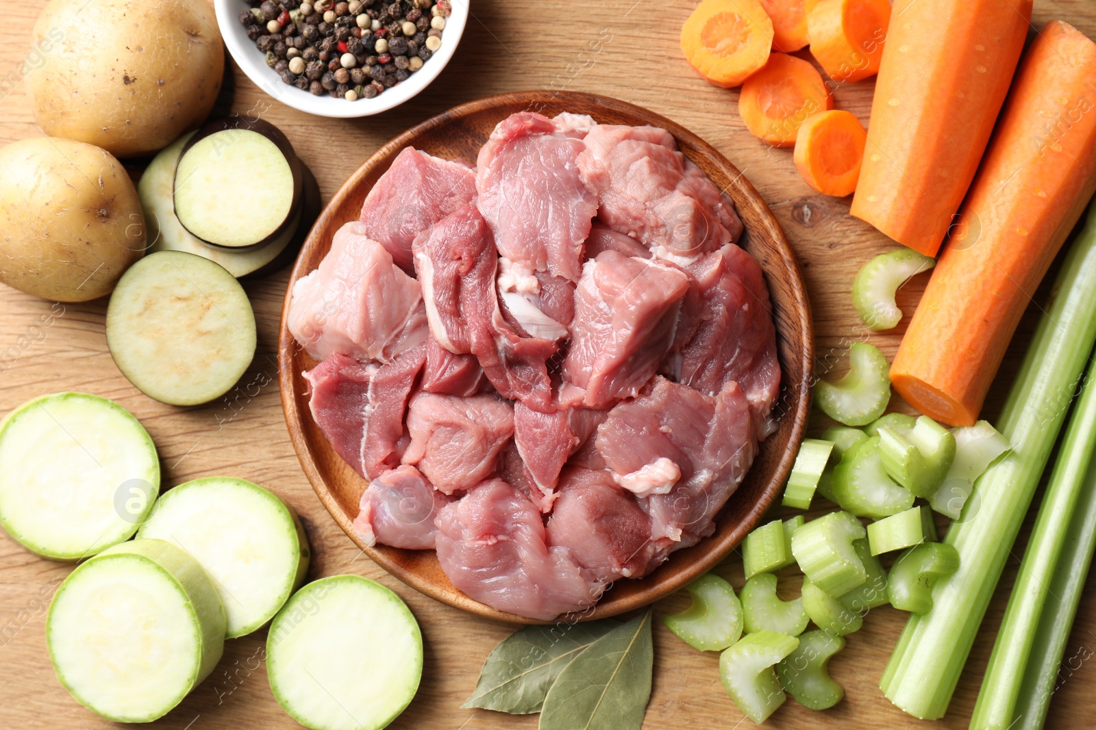 Photo of Cooking stew. Uncooked meat and vegetables on wooden table, flat lay