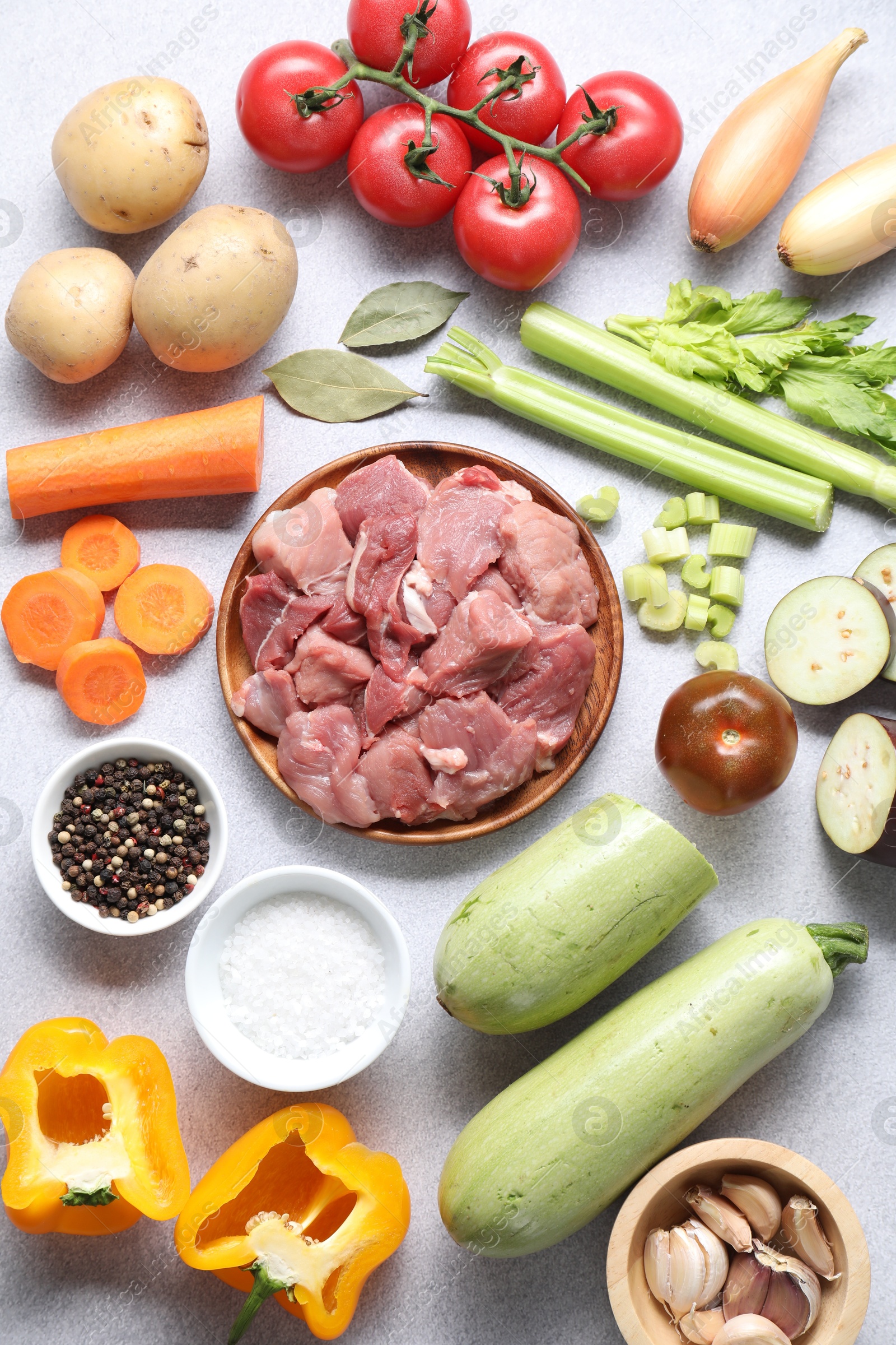 Photo of Cooking stew. Uncooked meat and vegetables on light grey table, flat lay