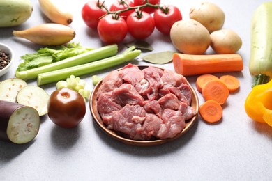 Photo of Cooking stew. Uncooked meat and vegetables on light grey table