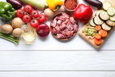 Photo of Cooking stew. Uncooked meat and vegetables on white wooden table, flat lay. Space for text