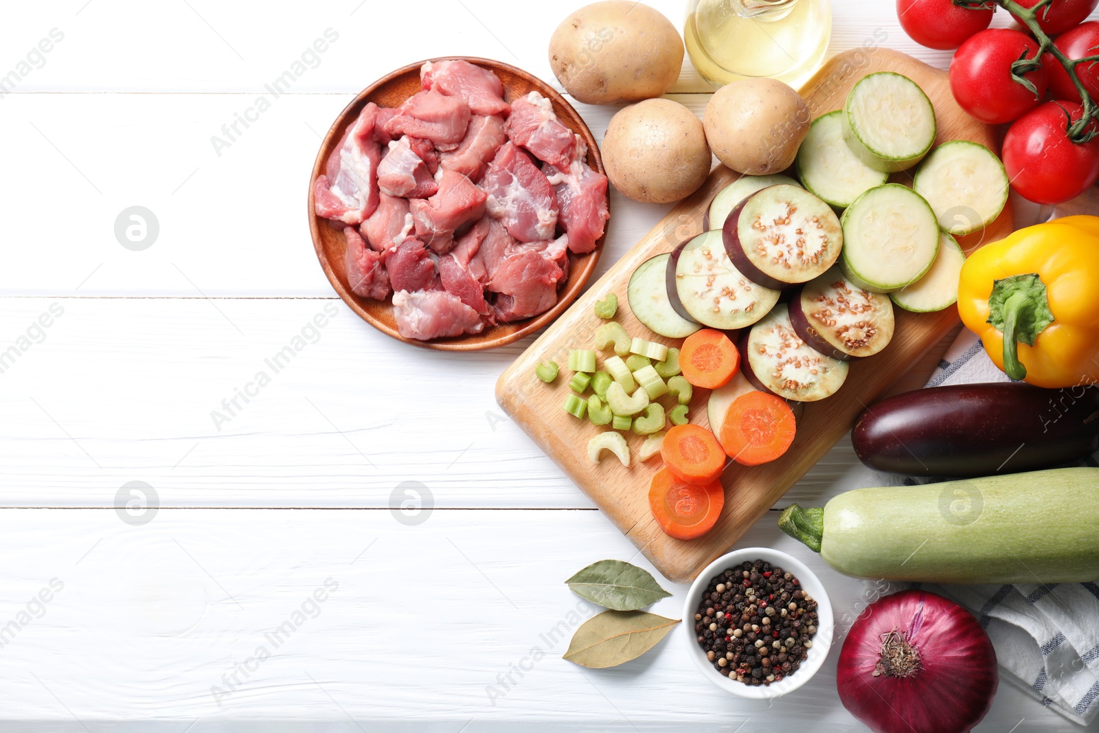 Photo of Cooking stew. Uncooked meat and vegetables on white wooden table, flat lay. Space for text