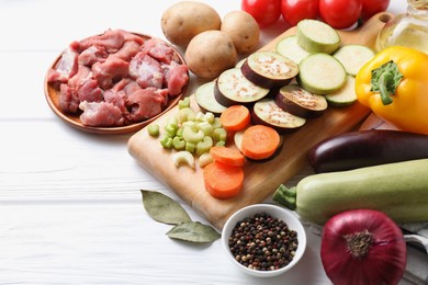 Photo of Cooking stew. Uncooked meat and vegetables on white wooden table