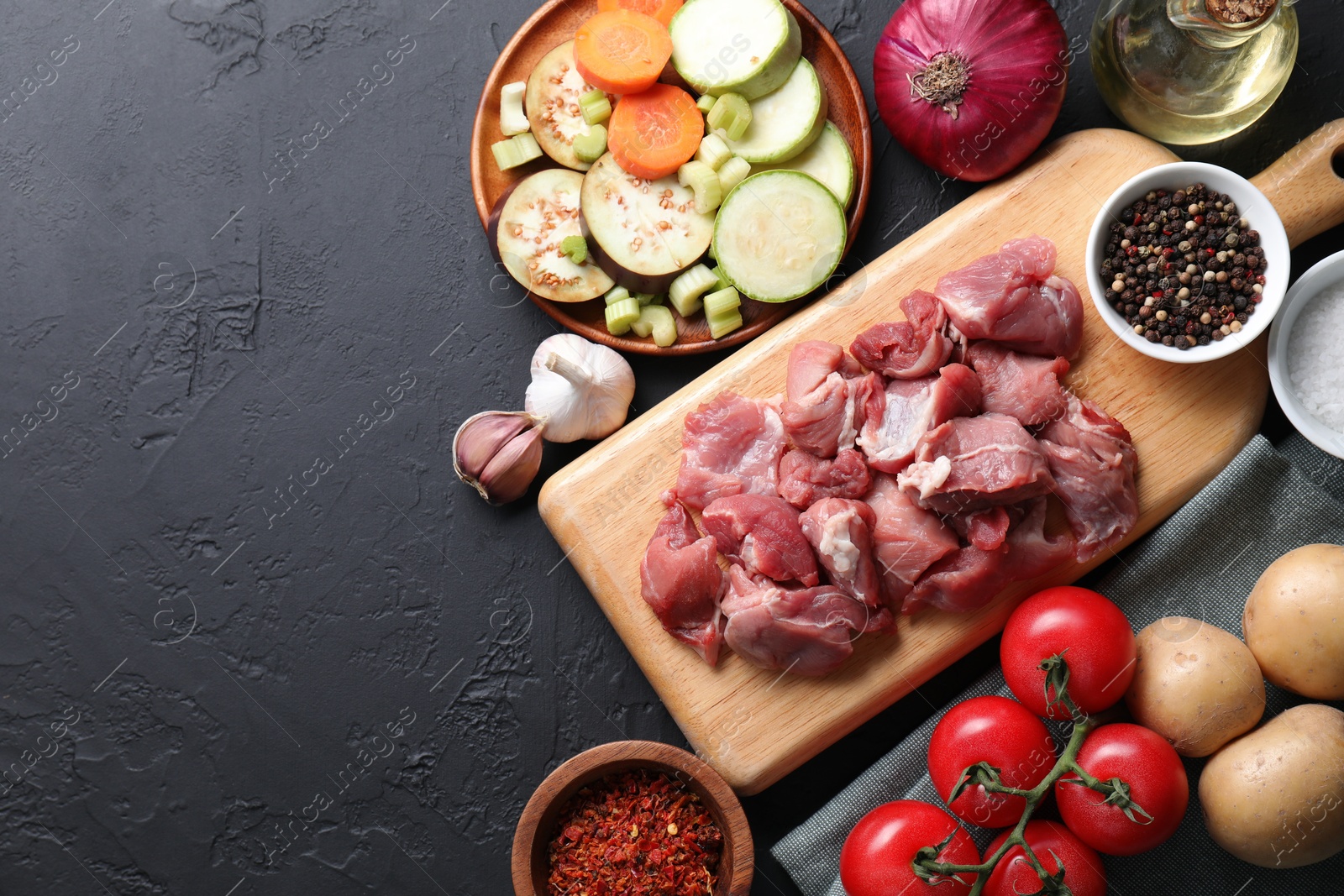 Photo of Cooking stew. Uncooked meat and vegetables on black table, flat lay. Space for text