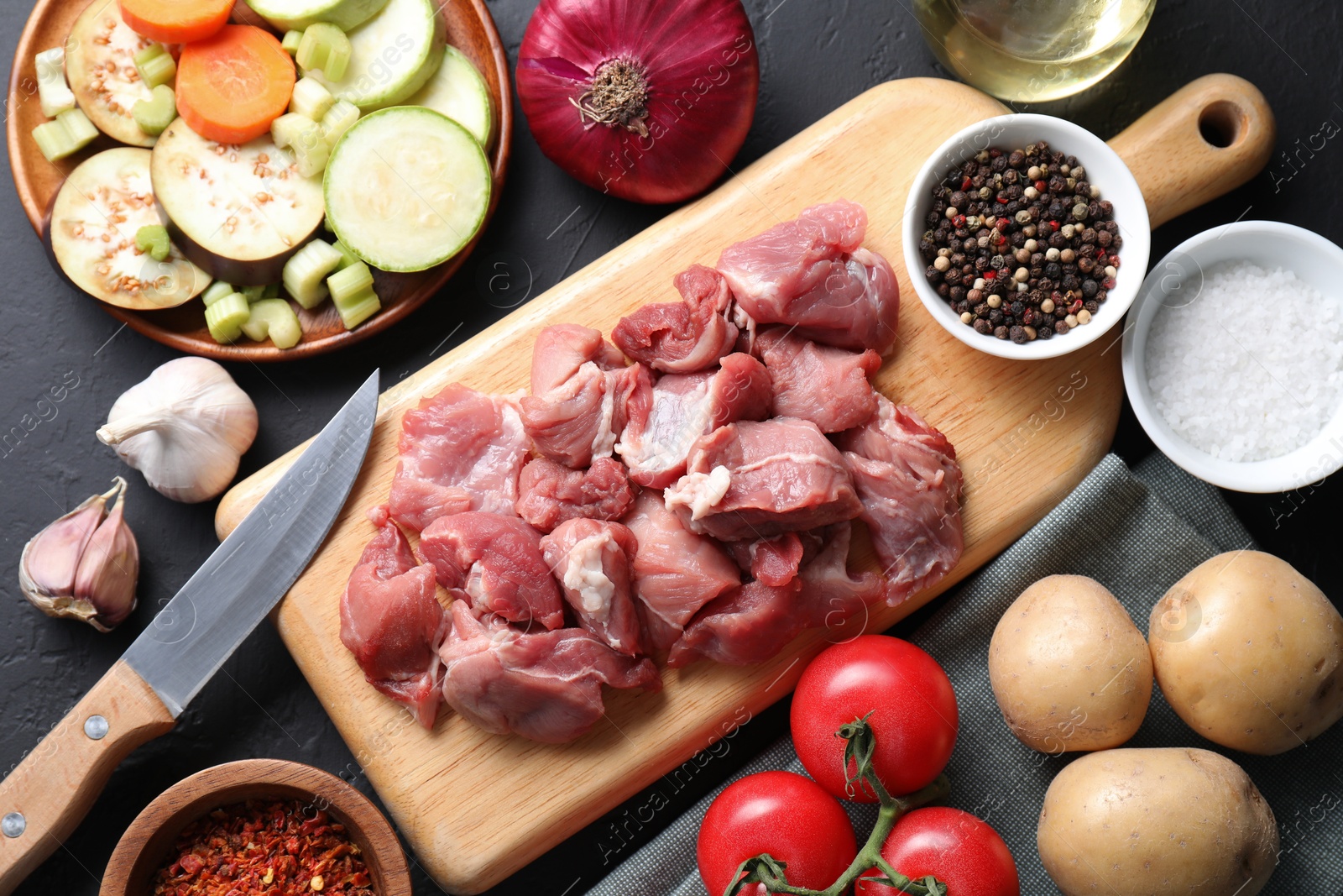 Photo of Cooking stew. Uncooked meat and vegetables on black table, flat lay