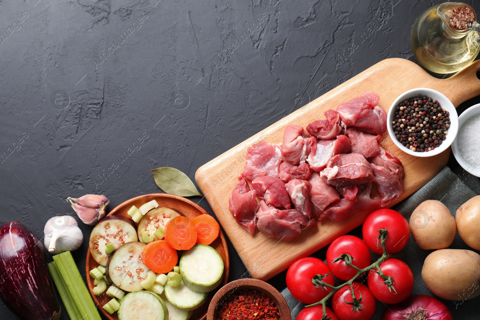 Photo of Cooking stew. Uncooked meat and vegetables on black table, flat lay. Space for text