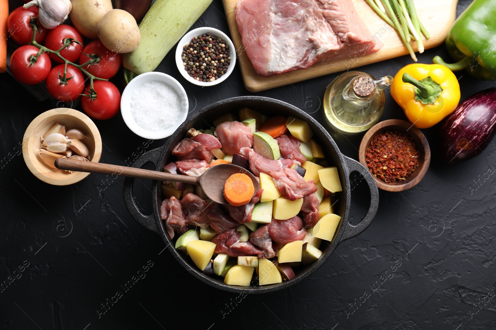 Photo of Cooking stew. Uncooked meat, vegetables and pot on black table, flat lay