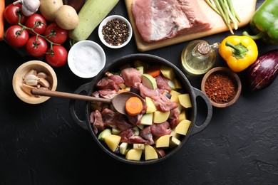 Photo of Cooking stew. Uncooked meat, vegetables and pot on black table, flat lay