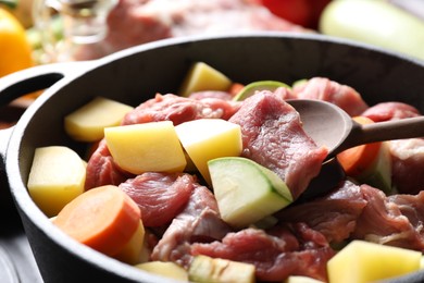 Photo of Cooking stew. Uncooked meat, vegetables and pot on black table, closeup