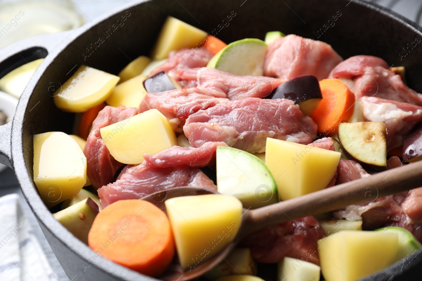 Photo of Cooking stew. Uncooked meat and vegetables in pot on table, closeup