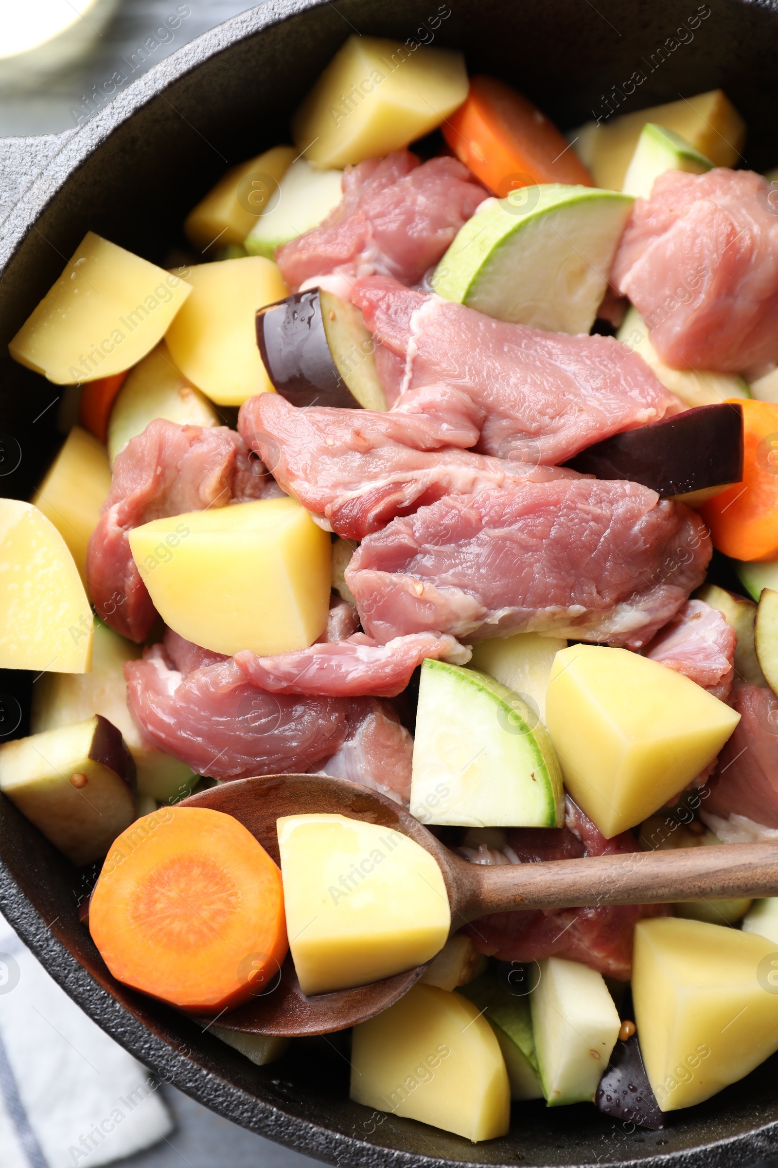 Photo of Cooking stew. Uncooked meat and vegetables in pot on table, top view