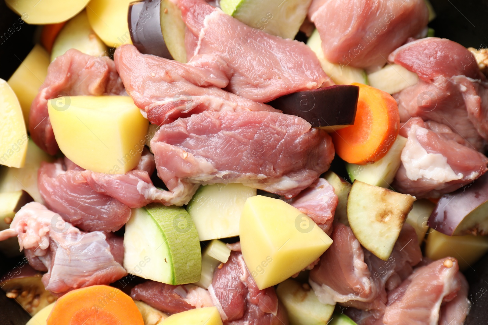 Photo of Cooking stew. Uncooked meat and vegetables in pot as background, closeup