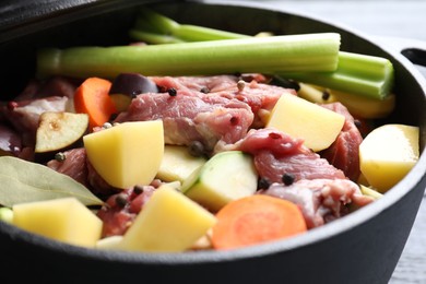 Photo of Cooking stew. Uncooked meat and vegetables in pot on table, closeup