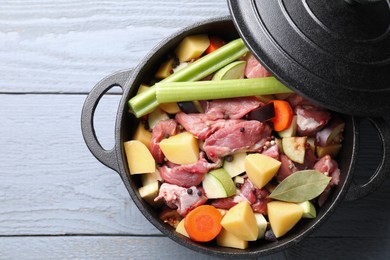 Photo of Cooking stew. Uncooked meat and vegetables in pot on light grey table, top view