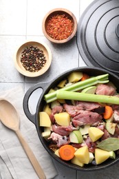 Photo of Cooking stew. Uncooked meat and vegetables in pot on white tiled table, flat lay