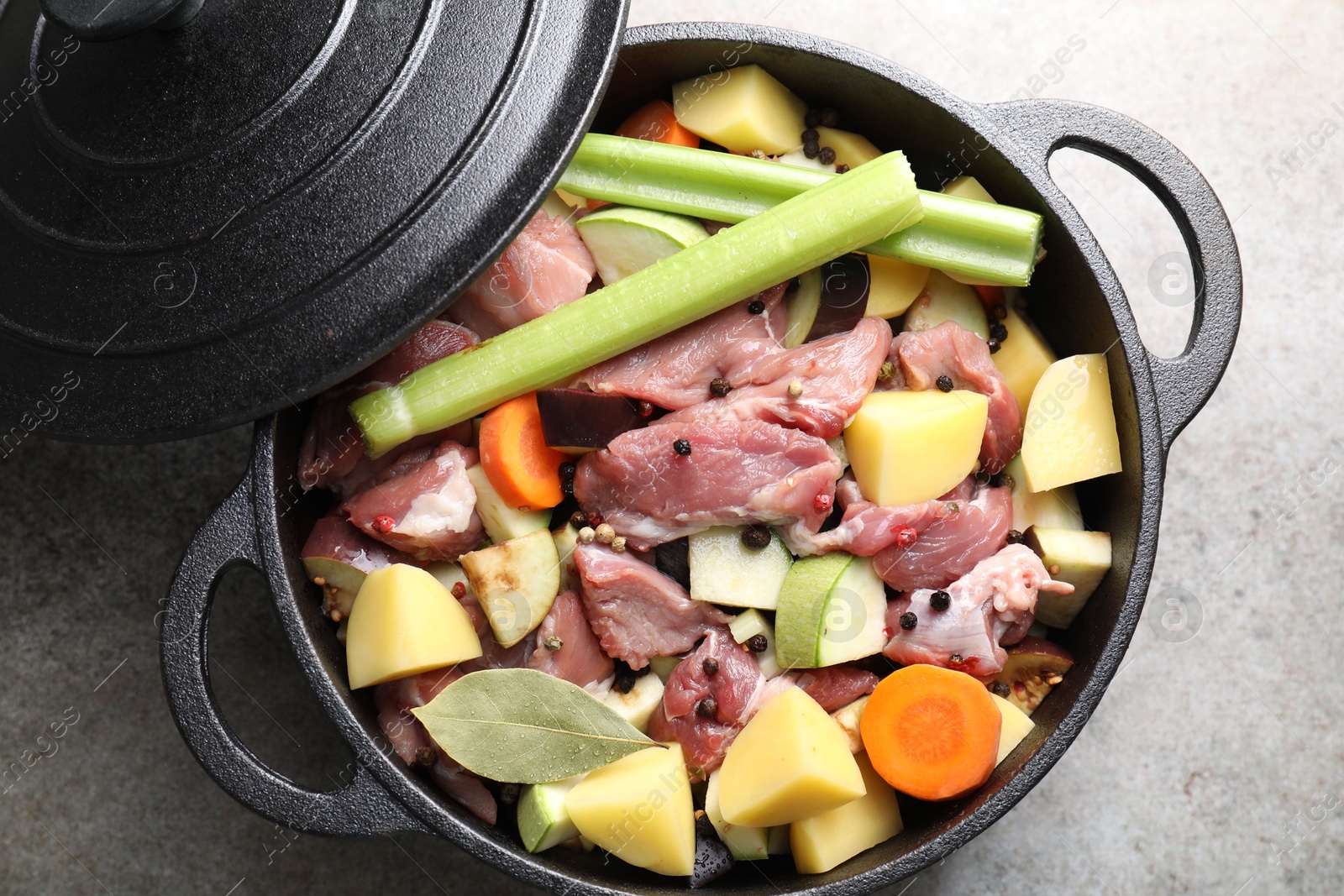 Photo of Cooking stew. Uncooked meat and vegetables in pot on light grey table, top view