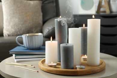 Beautiful burning candles and matches on light table indoors