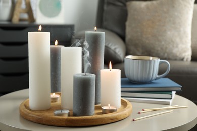 Beautiful burning candles and matches on light table indoors