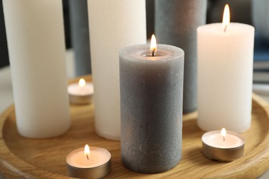 Beautiful burning candles on wooden board, closeup