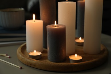 Beautiful burning candles and matches on table indoors, closeup