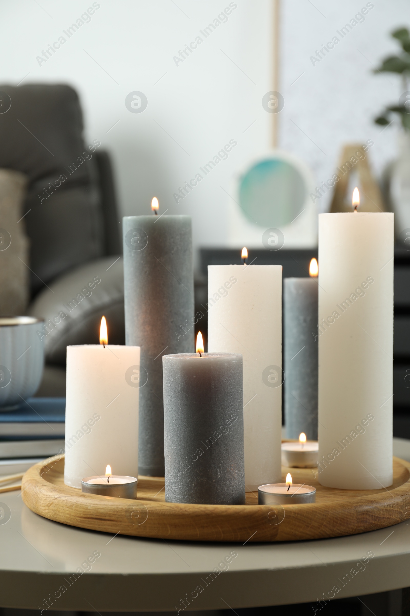 Photo of Beautiful burning candles on light table in room