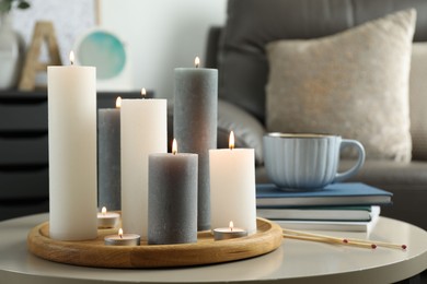 Beautiful burning candles and matches on light table indoors