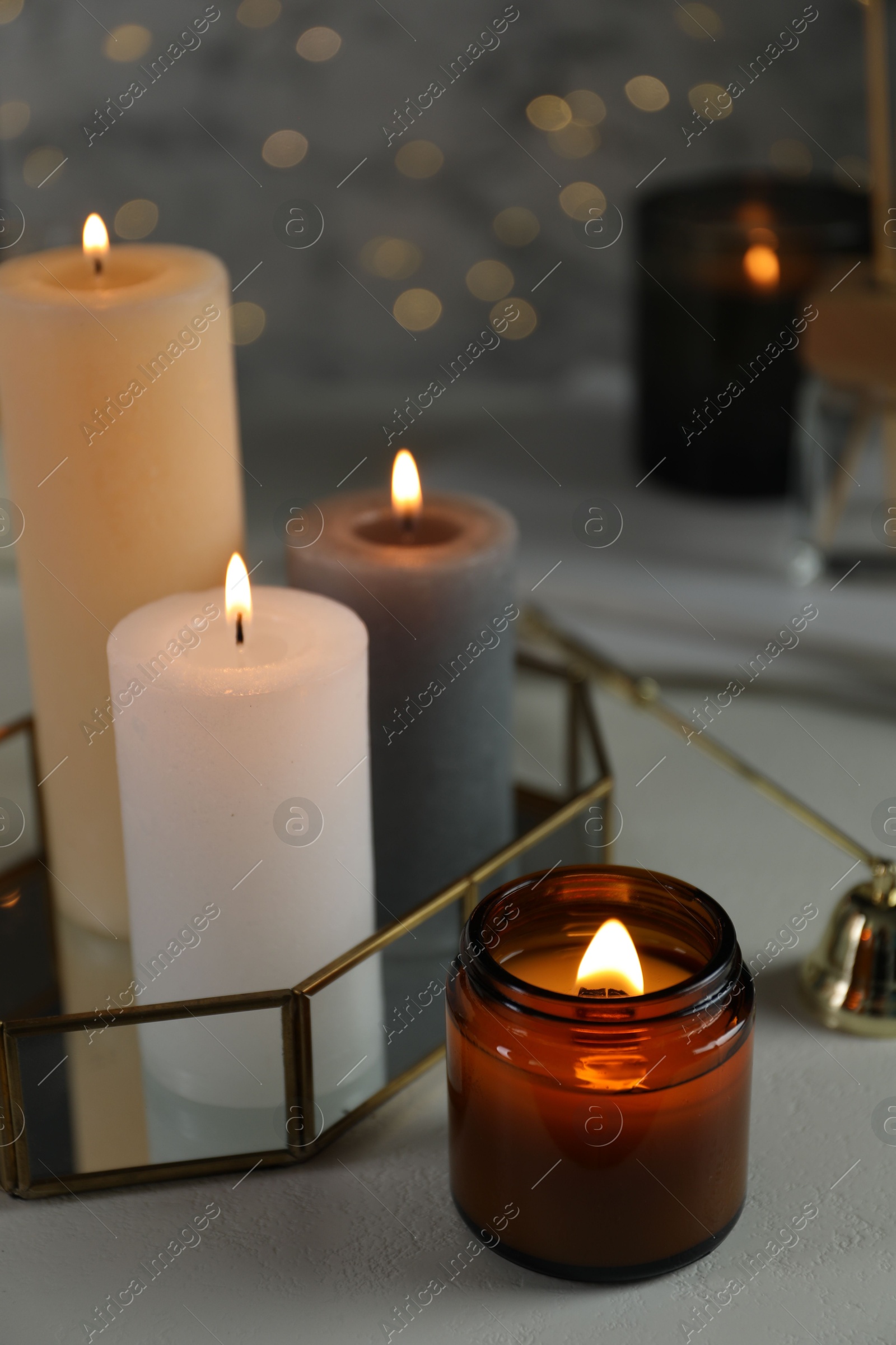 Photo of Beautiful burning candles on table against blurred lights, closeup