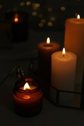 Beautiful burning candles on table against blurred lights, closeup