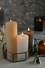 Photo of Beautiful burning candles on table against blurred lights, closeup