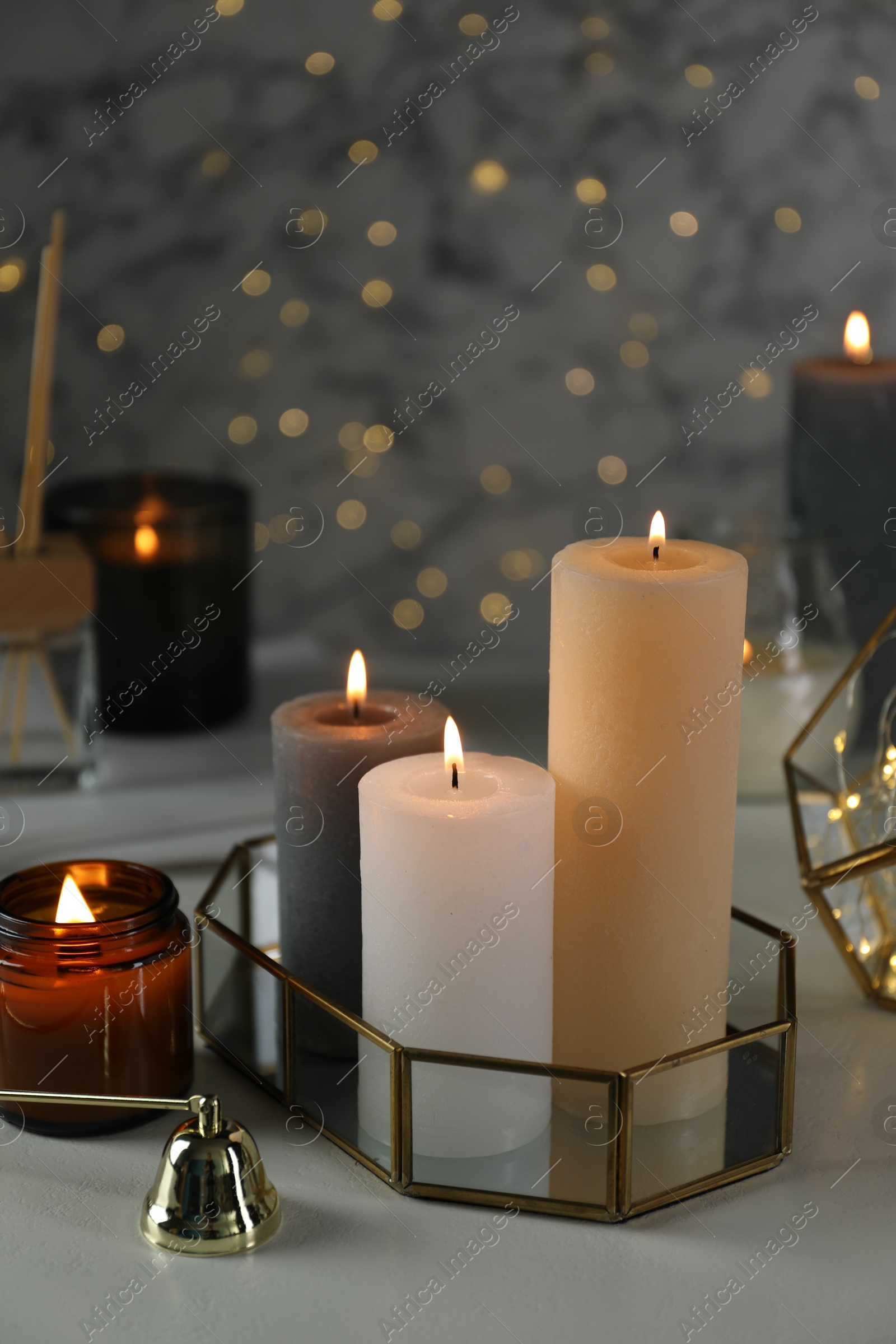 Photo of Beautiful burning candles on table against blurred lights, closeup