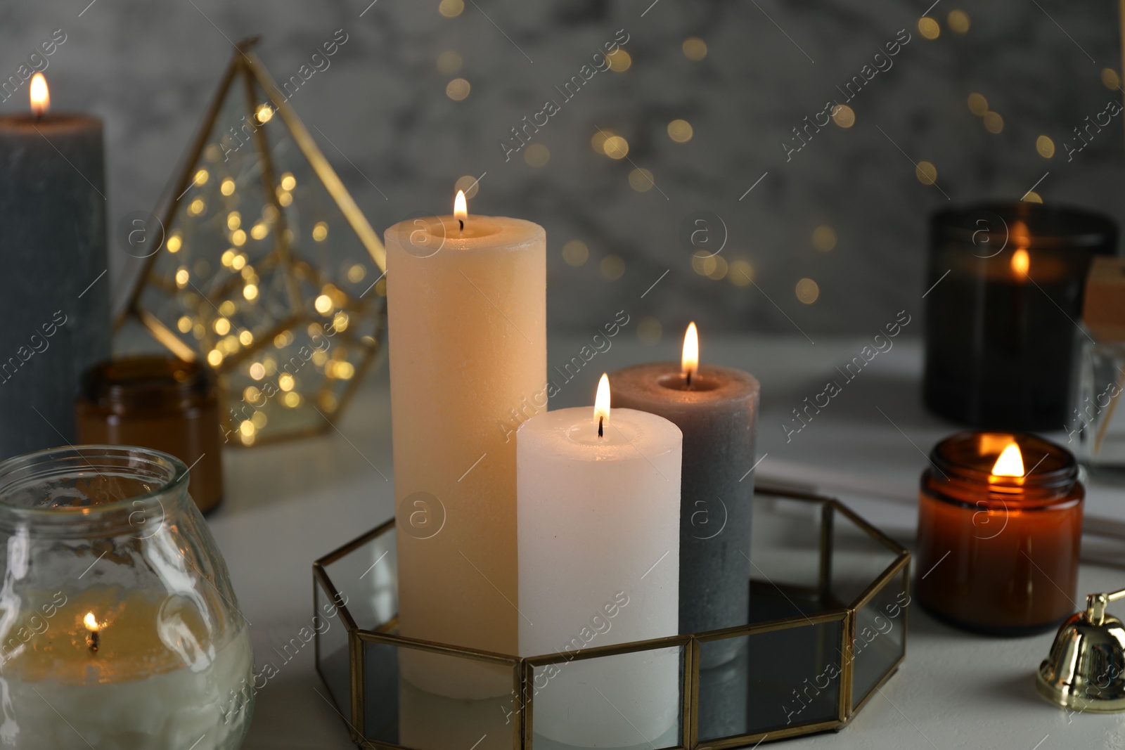 Photo of Beautiful burning candles on table against blurred lights, closeup