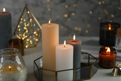 Beautiful burning candles on table against blurred lights, closeup